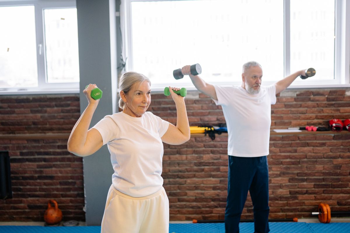 An elderly man and woman working out with dumbbells