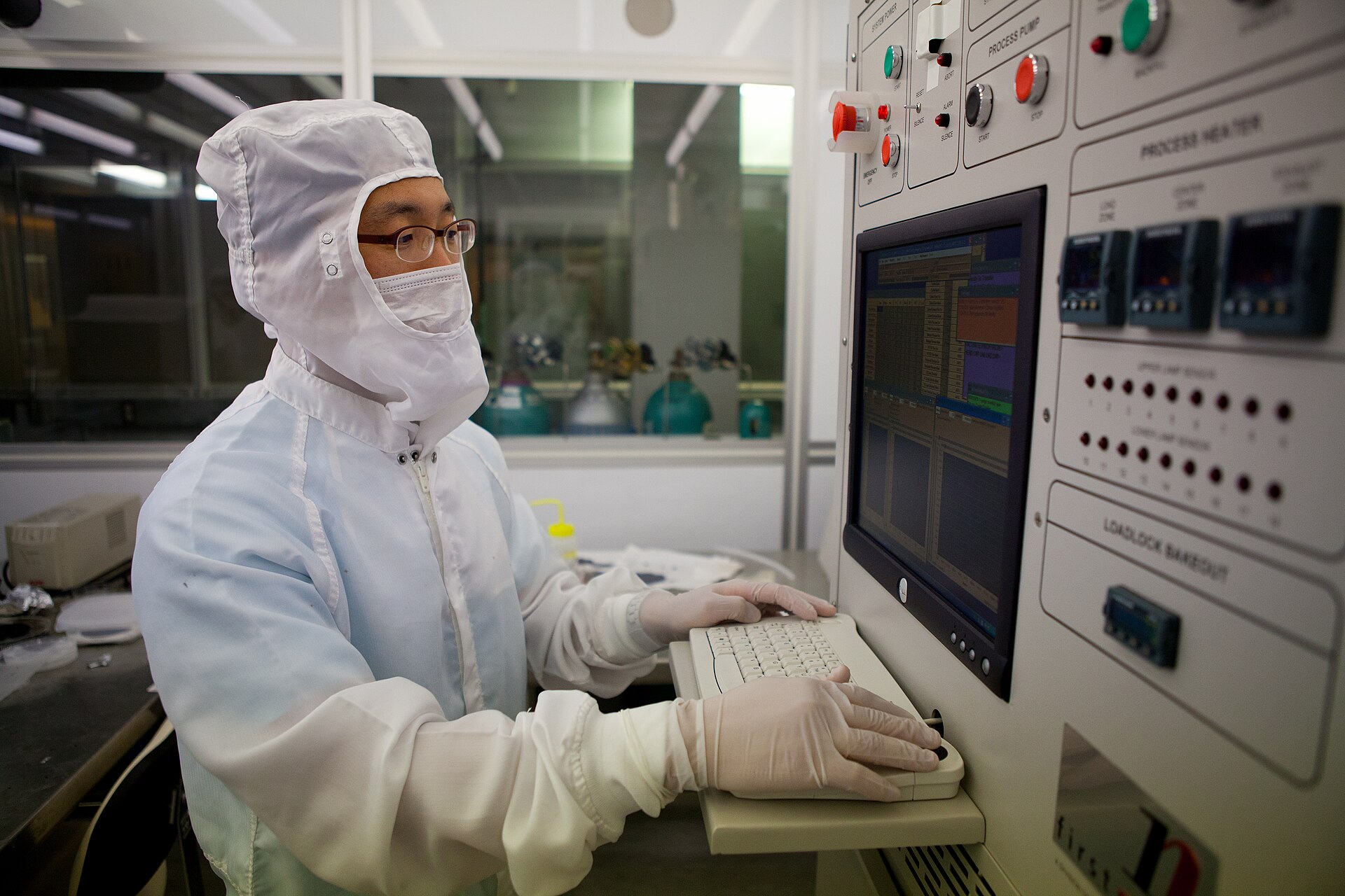 technician operating fabrication equipment under yellow cleanroom lighting, related to on-device AI memory chip research
