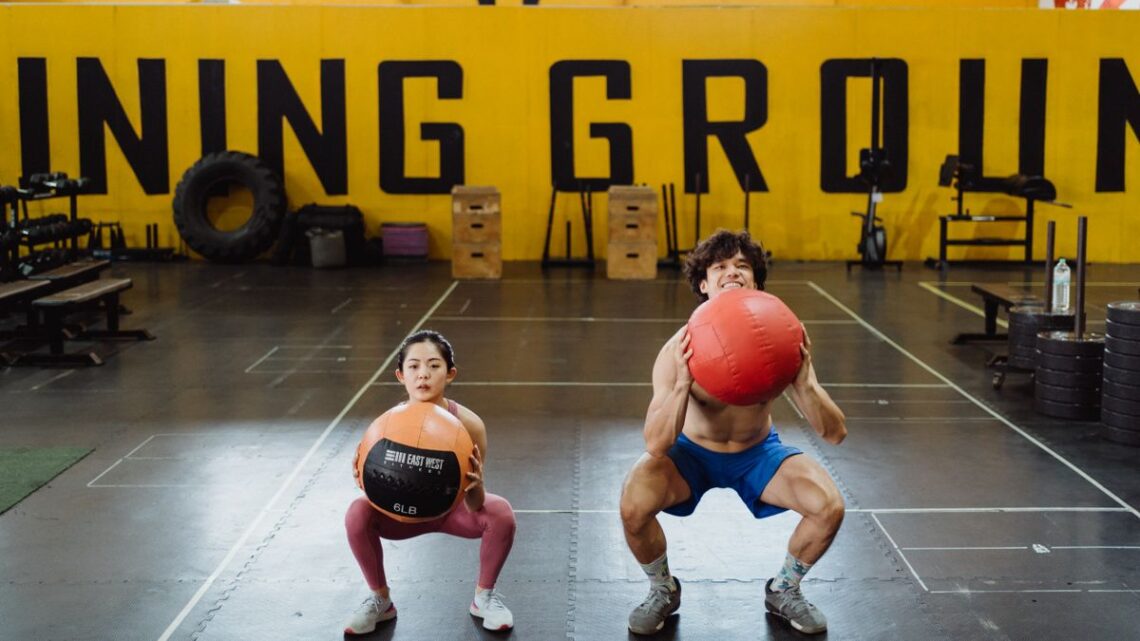 Two people holding a squat position in a gym, illustrating squat depth 스쿼트 무릎 통증